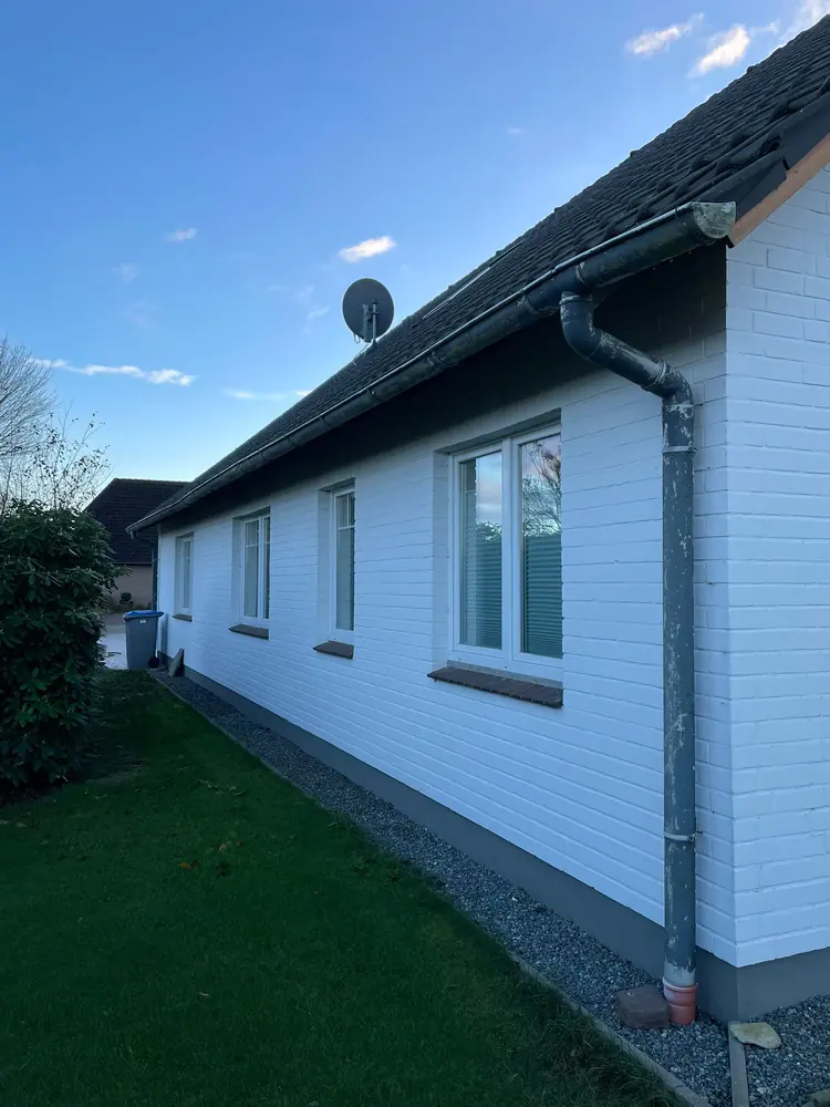 Weiß gestrichenes Haus mit neuer Dachrinne und Fallrohr